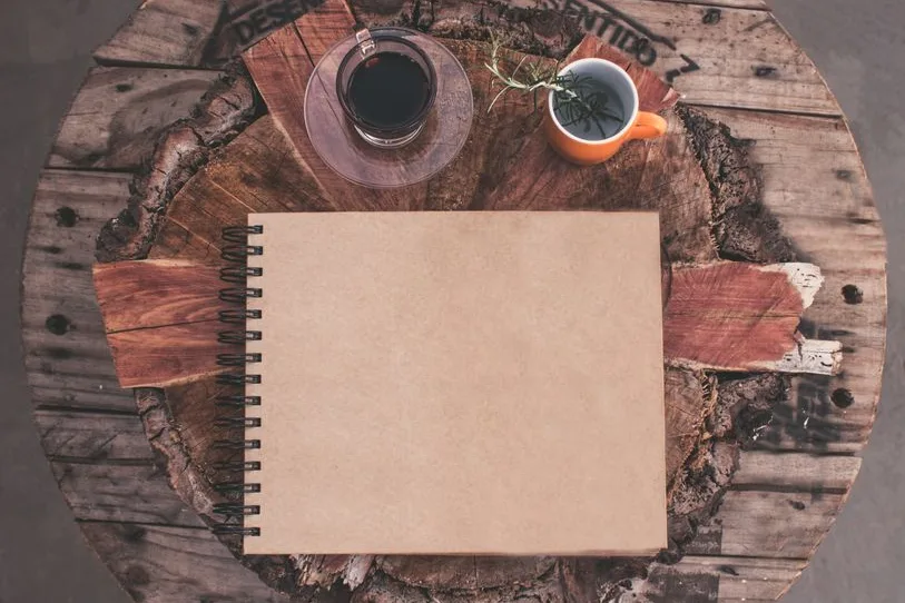 Carnet ouvert, tasse de tisane et café sur une table en bois rustique